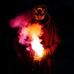person in black mask holding purple and pink smoke
